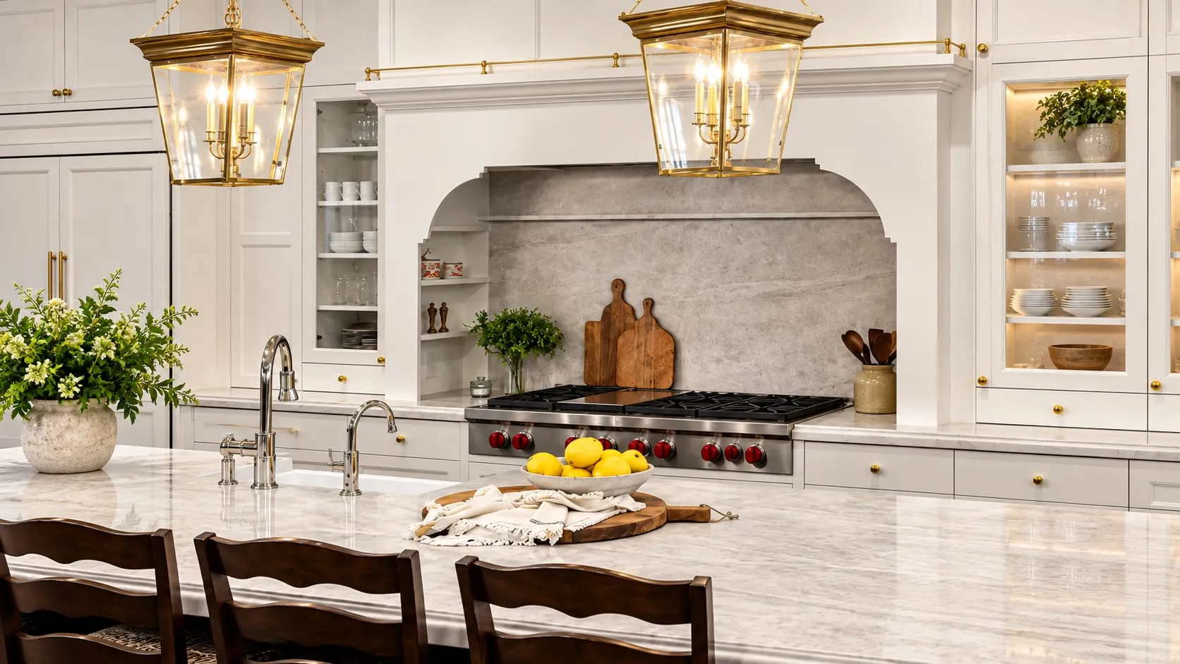 Classic white kitchen with a veined stone island beneath brass lantern pendants